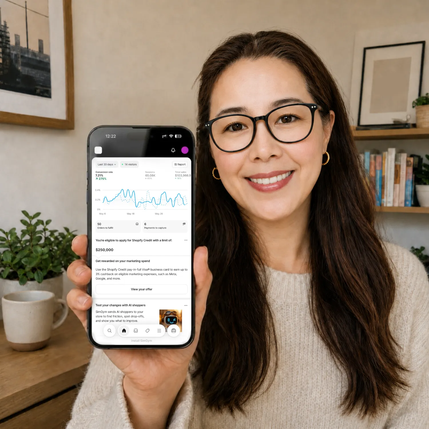 Founder holding a phone showing a Shopify analytics dashboard